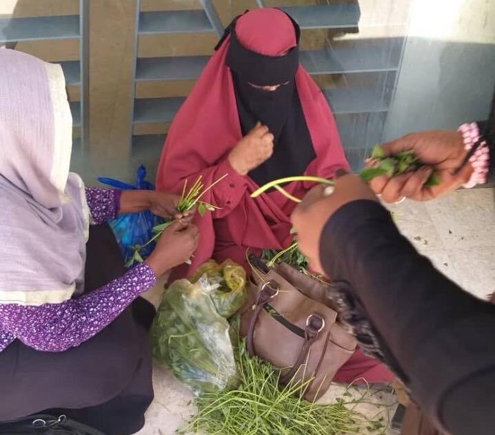 بالصور.. أثناء انتظارها في صفوف الصرافات الآلية.. سيدة سودانية تباشر عمل الغداء و (توريق) الملوخية أمام واجهة بنك سيدة تباشر عملها1